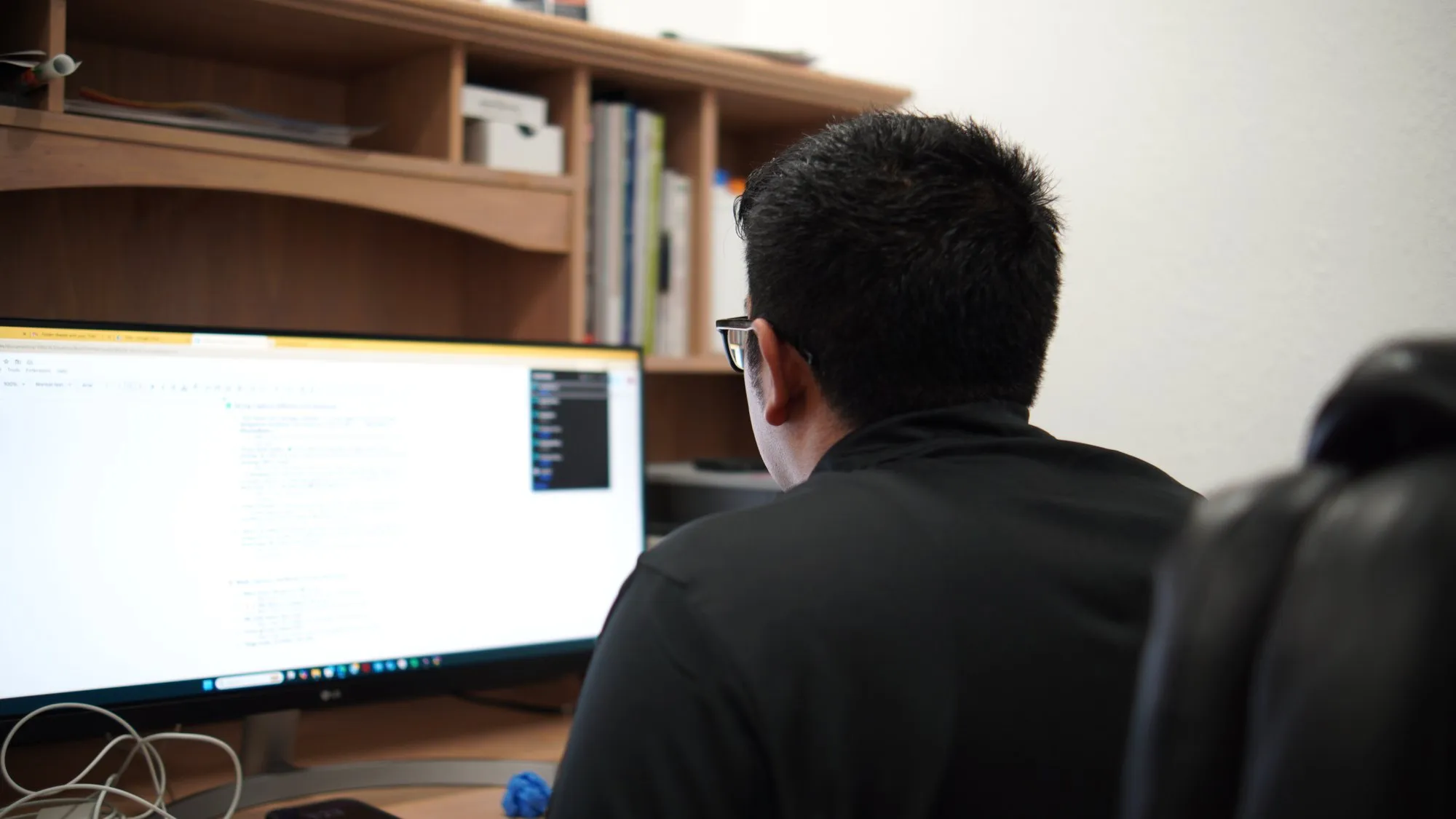 Anthony at his desk preparing logo artwork on a computer before it goes to the machine
